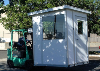 A forklift moving a modular guard house.