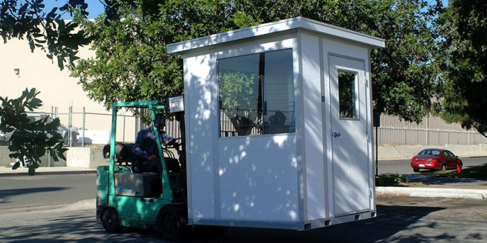 A forklift moving a modular guard house.