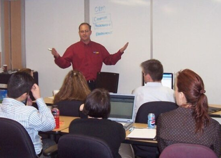 A teacher in front of a whiteboard in a modular training room.