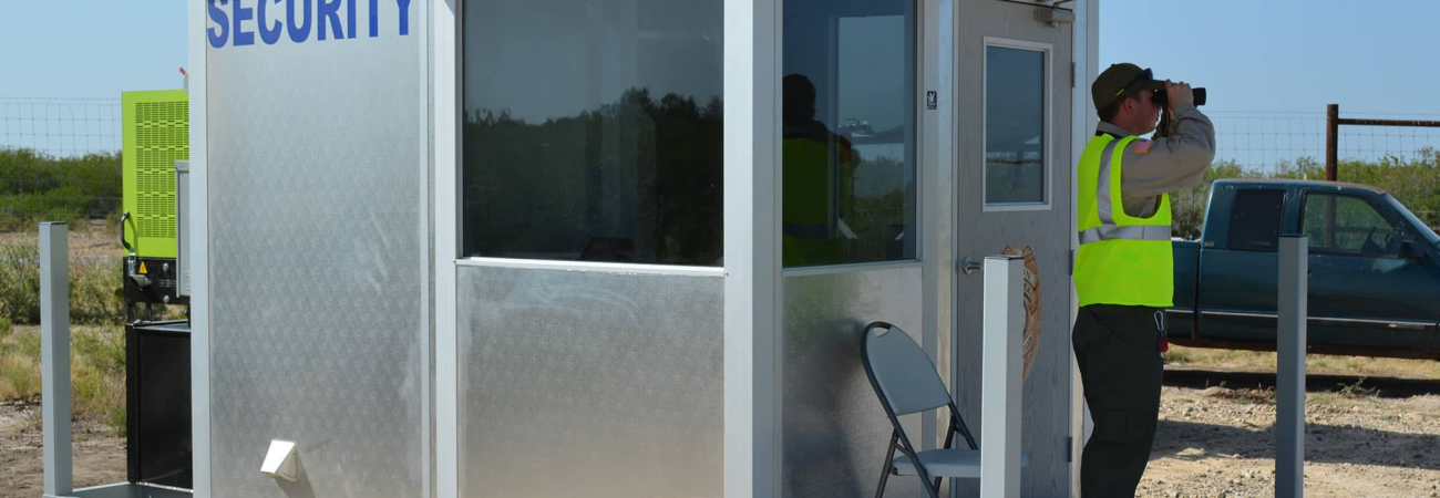 An operational guard shack, with a security guard looking out using a pair of binoulars.
