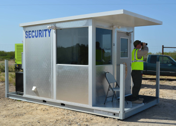 An operational guard shack, with a security guard looking out using a pair of binoulars.