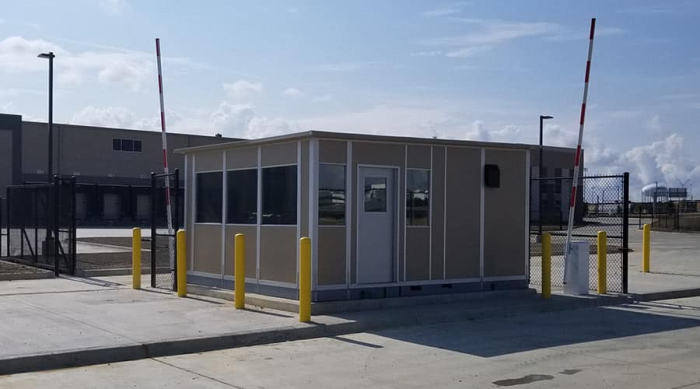 A beige-colored guard house on the edge of a gated area.