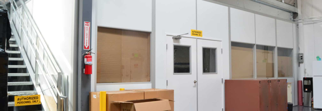 Modular mezzanine structure with storage boxes and equipment on the ground level in an industrial facility.