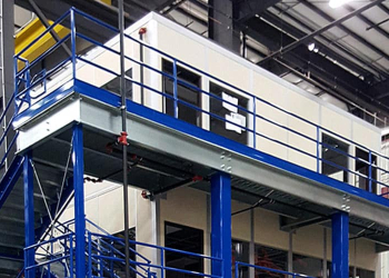 A blue steel mezzanine structure with railings and stairs inside a warehouse.