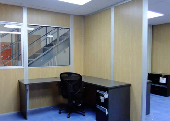 A desk and chair sits inside modular office partitions.