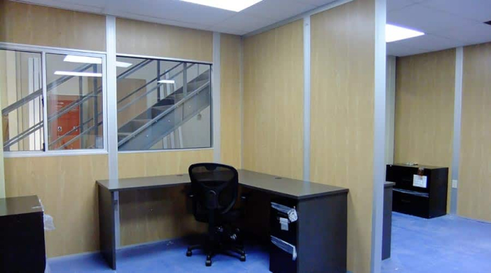 A desk and chair sits inside modular office partitions.