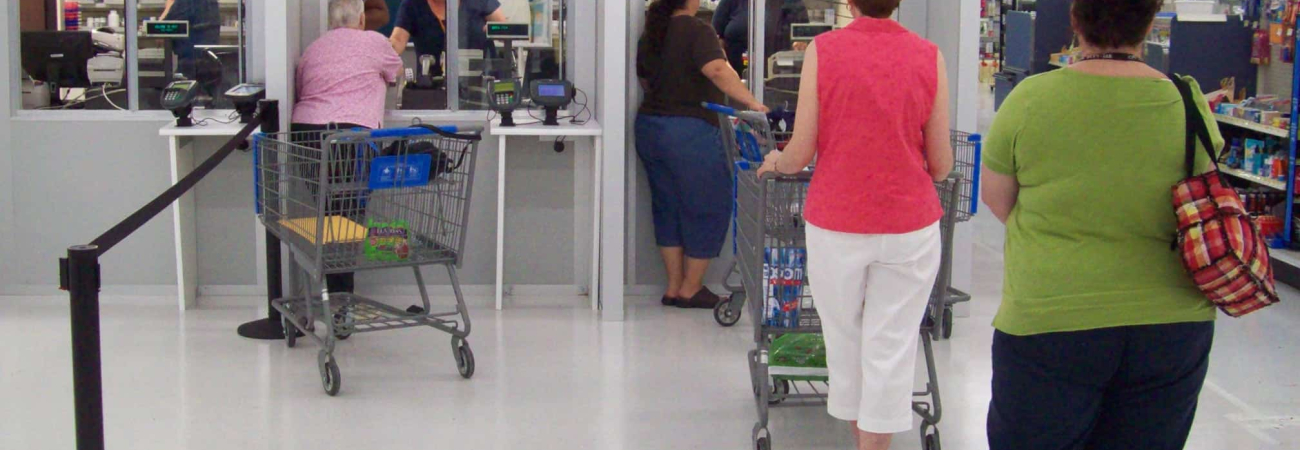 Modular pharmacy checkout counters with customers waiting in line, featuring prefabricated enclosures by Allied Modular.