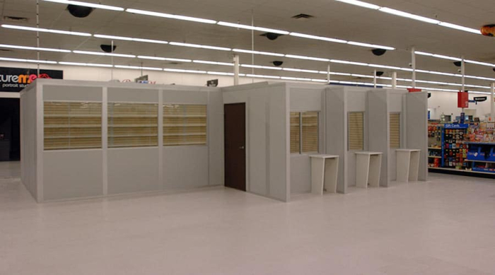 Modular retail office enclosure by Allied Modular inside a store, featuring prefabricated walls, windows, and service counters.