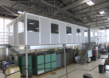 A gray modular office on top of a freestanding mezzanine.