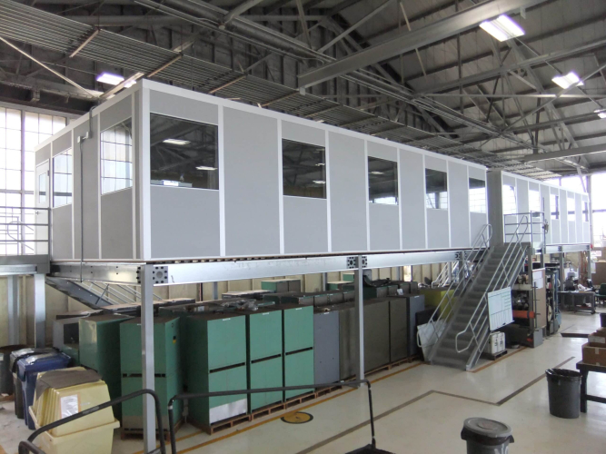 A gray modular office on top of a freestanding mezzanine.