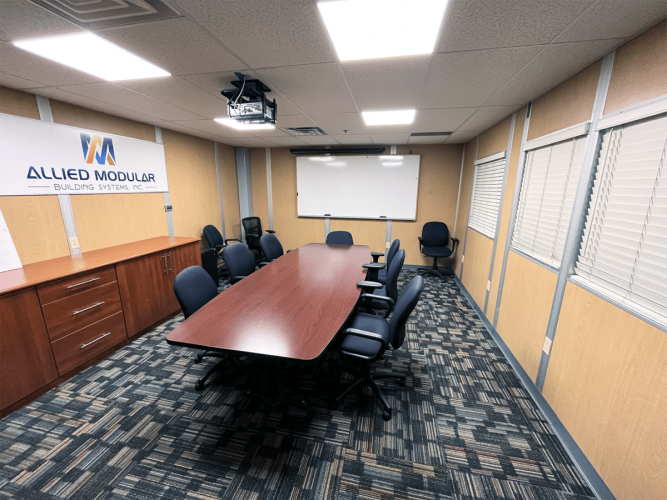 A modular meeting/conference room, with a wooden table in the middle.