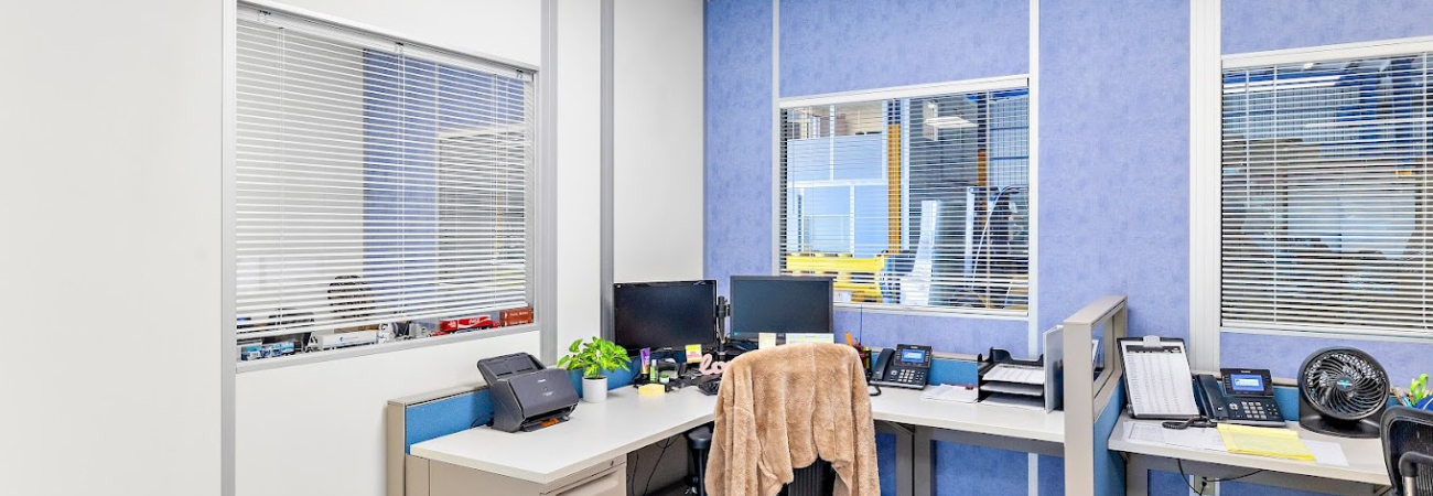 A modular office interior by Allied Modular, featuring a compact workspace with two desks, office equipment, and blue and white wall panels.