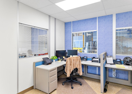 A modular office interior by Allied Modular, featuring a compact workspace with two desks, office equipment, and blue and white wall panels.