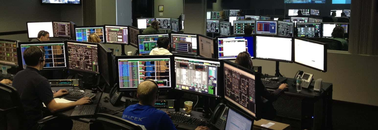 A busy control room with many people and computers.