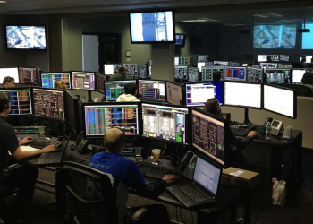 A busy control room with many people and computers.