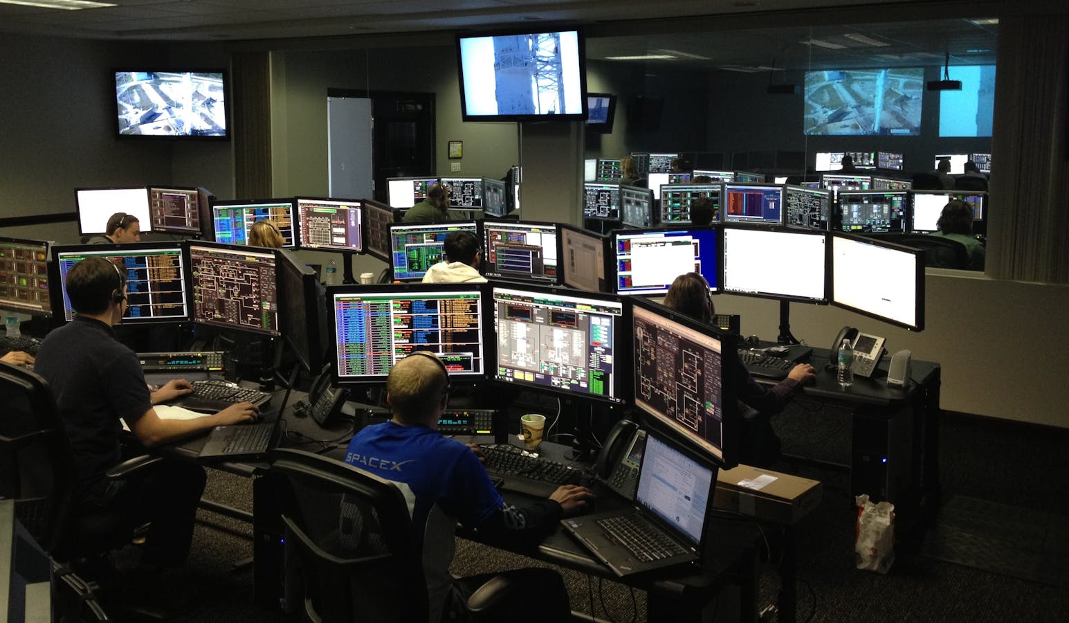 A busy control room with many people and computers.