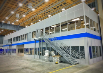 A modern, industrial-style office space with an external staircase leading to a second-floor area inside a large warehouse.