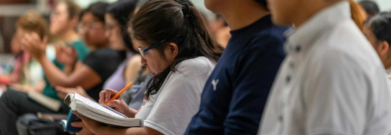 A large classroom full of students taking notes.