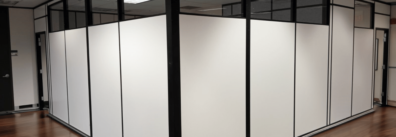 A modular office space with white partitions and glass panels.
