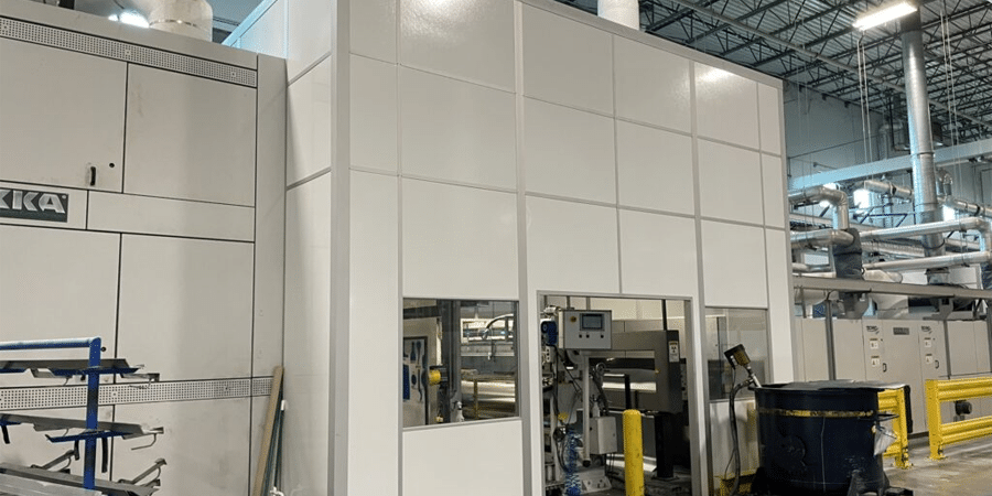 A large modular machine enclosure in a warehouse, designed to isolate machinery and reduce noise and emissions.