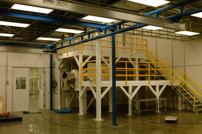 Industrial mezzanine structure with yellow guardrails and stair access, built for additional workspace or equipment storage in a manufacturing or industrial setting.