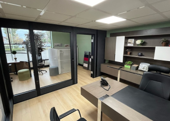 Modern office space featuring freestanding walls with full glass partitions, providing a clear division between the workspace and meeting area while maintaining an open, inviting atmosphere.