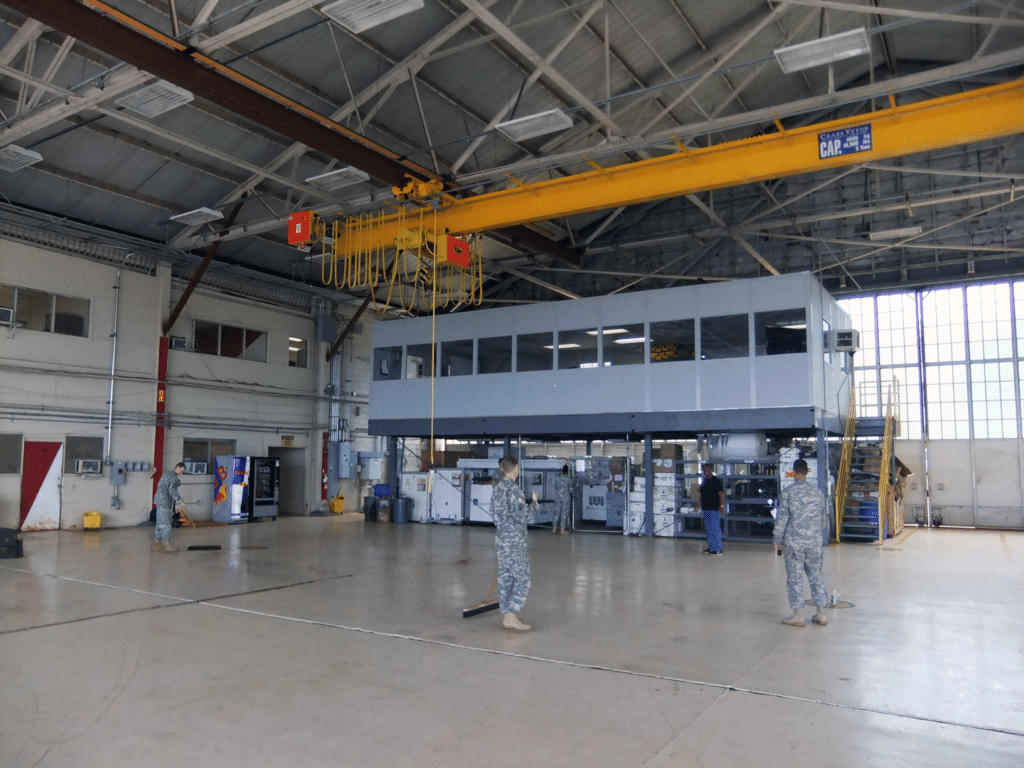 Allied Modular warehouse mezzanine with enclosed office space elevated above a production floor inside an industrial facility.