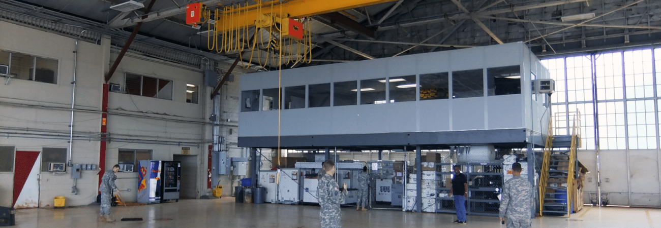 Allied Modular warehouse mezzanine with enclosed office space elevated above a production floor inside an industrial facility.
