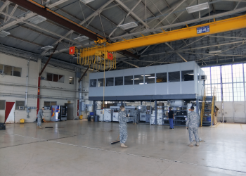 Allied Modular warehouse mezzanine with enclosed office space elevated above a production floor inside an industrial facility.