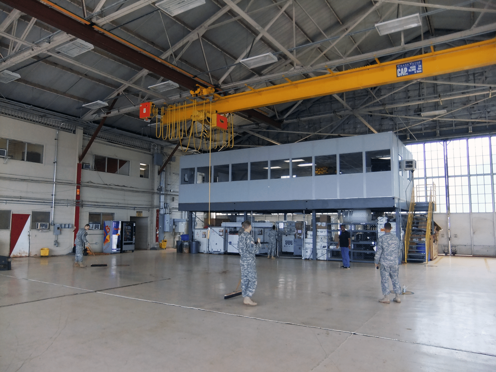 warehouse-mezzanine Allied Modular warehouse mezzanine with enclosed office space elevated above a production floor inside an industrial facility.