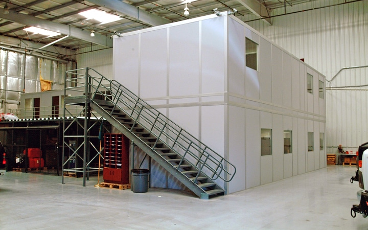 Two-story modular office building by Allied Modular, installed inside a warehouse with an external metal staircase.