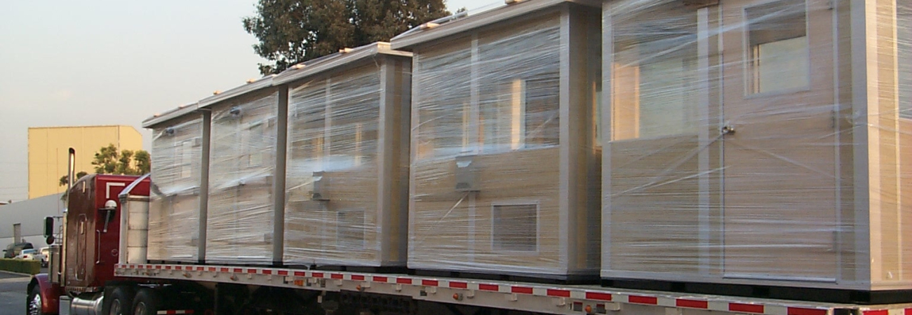 Allied Modular prefabricated buildings loaded on a flatbed truck for delivery.