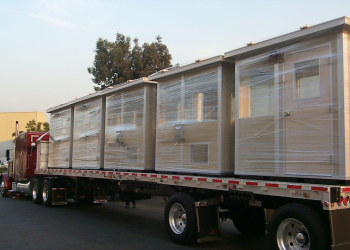 Allied Modular prefabricated buildings loaded on a flatbed truck for delivery.