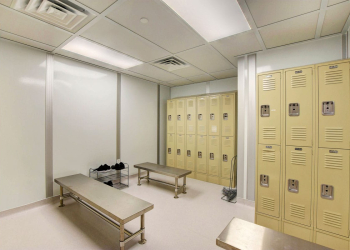 Modular locker room with stainless steel benches, beige lockers, and ceiling ventilation for controlled environments.