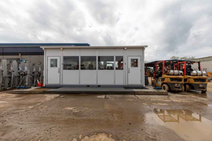 Exterior view of a portable construction office set up on a job site, surrounded by equipment and machinery.