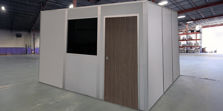 A quick-ship modular office by Allied Modular, installed inside a warehouse. The structure features a solid door, a window, and durable panel walls, providing a fast and efficient workspace solution.