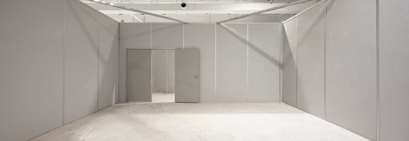 Allied Modular installation of a gray modular wall system inside a warehouse space with integrated door and clean interior finish.