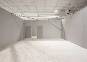 Allied Modular installation of a gray modular wall system inside a warehouse space with integrated door and clean interior finish.