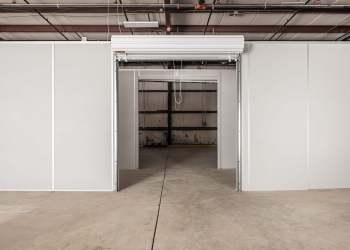 Modular warehouse partition with a roll-up door, dividing a large open space into smaller, customizable sections.