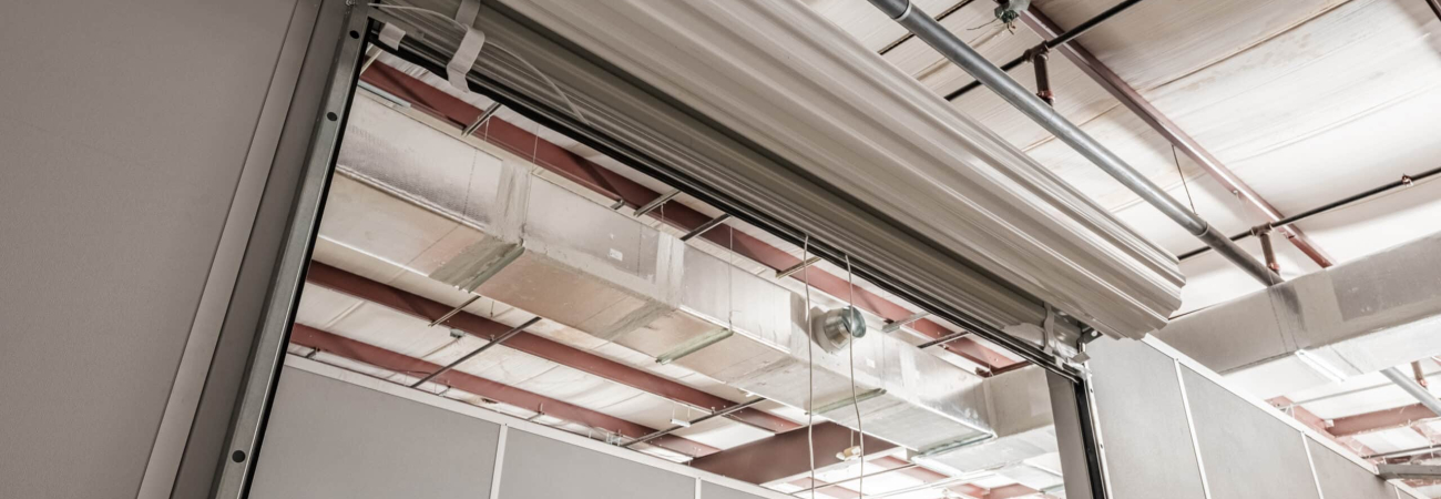An interior shot of an Allied Modular modular enclosure featuring clean, prefabricated wall panels, steel support beams, and an overhead roll-up door. The factory-built, reusable wall systems shown here are the type of modular construction that can earn up to 25 points toward LEED certification.