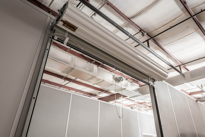An interior shot of an Allied Modular modular enclosure featuring clean, prefabricated wall panels, steel support beams, and an overhead roll-up door. The factory-built, reusable wall systems shown here are the type of modular construction that can earn up to 25 points toward LEED certification.