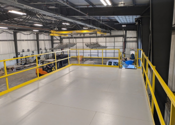 Allied Modular pallet racking mezzanine platform installed in a warehouse with yellow guardrails and overhead equipment.
