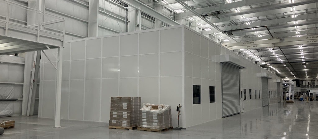 Modular warehouse enclosure with roll-up door and windows built by Allied Modular inside a large industrial facility.