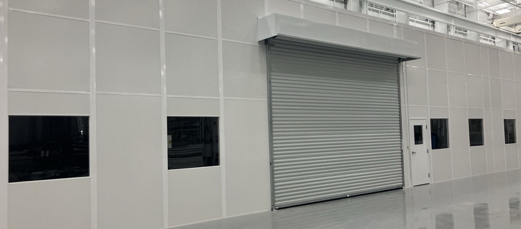 Large sustainable modular building with roll-up door and windows, built by Allied Modular inside an industrial facility.
