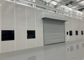 Large sustainable modular building with roll-up door and windows, built by Allied Modular inside an industrial facility.