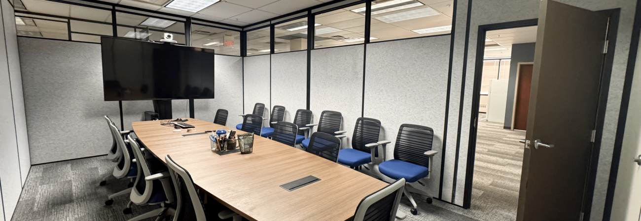 Modular conference room by Allied Modular featuring a long meeting table, ergonomic chairs, and partition walls with upper glass panels.
