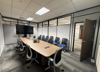 Modular conference room by Allied Modular featuring a long meeting table, ergonomic chairs, and partition walls with upper glass panels.