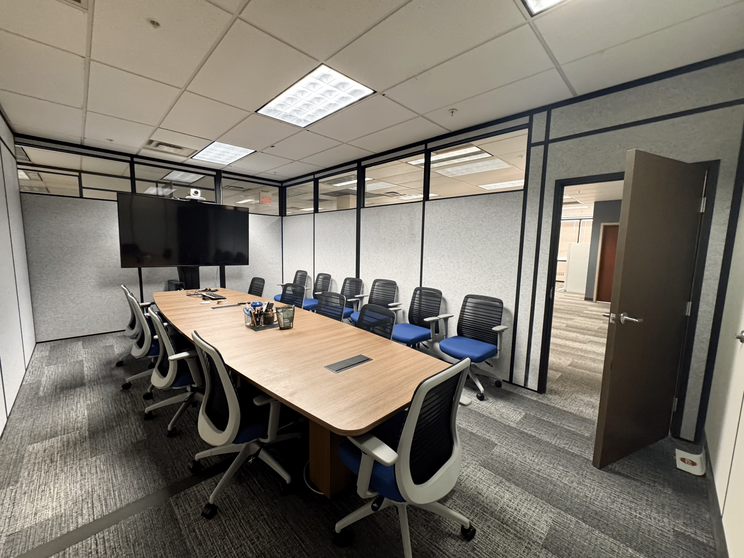 Modular conference room by Allied Modular featuring a long meeting table, ergonomic chairs, and partition walls with upper glass panels.