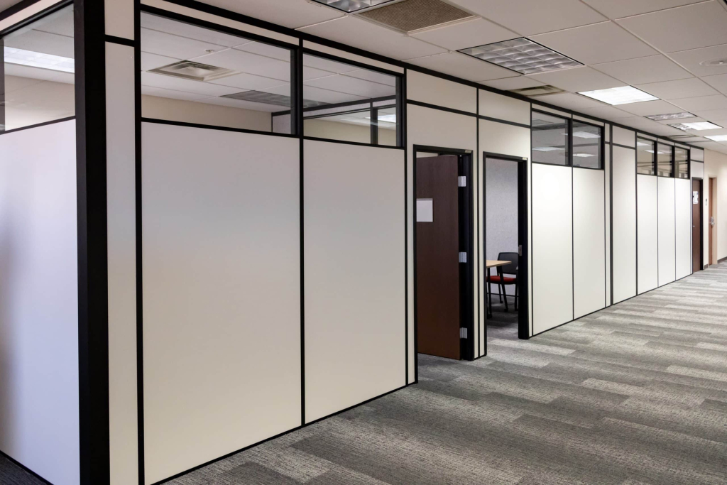 Office hallway with modular partition walls and private offices built by Allied Modular using black-framed white panels and upper glass inserts.