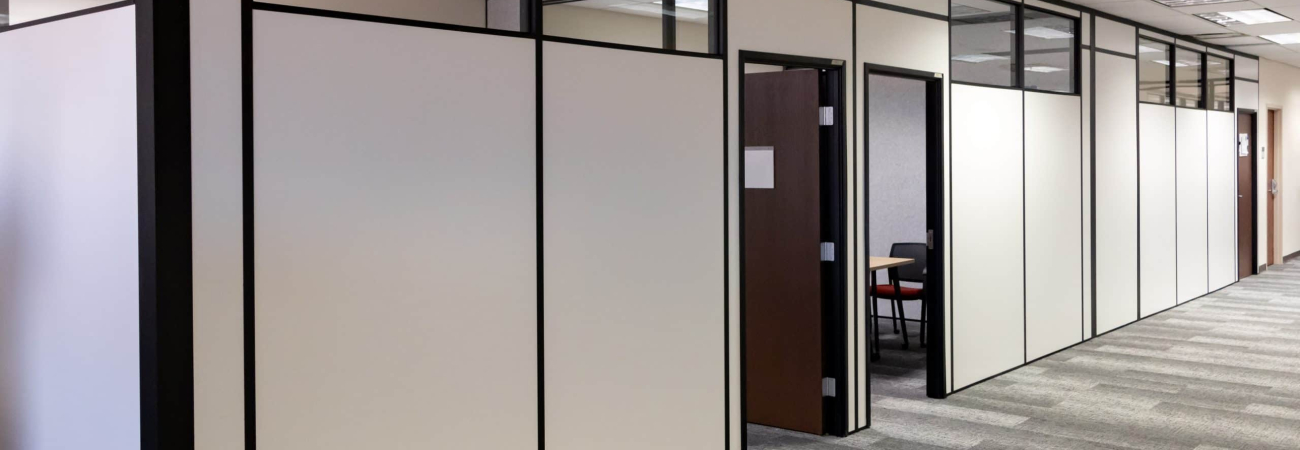 Office hallway with modular partition walls and private offices built by Allied Modular using black-framed white panels and upper glass inserts.